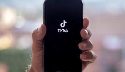 Ihmisen käsi pitelee älypuhelinta, jonka näytöllä on Tiktokin logo.